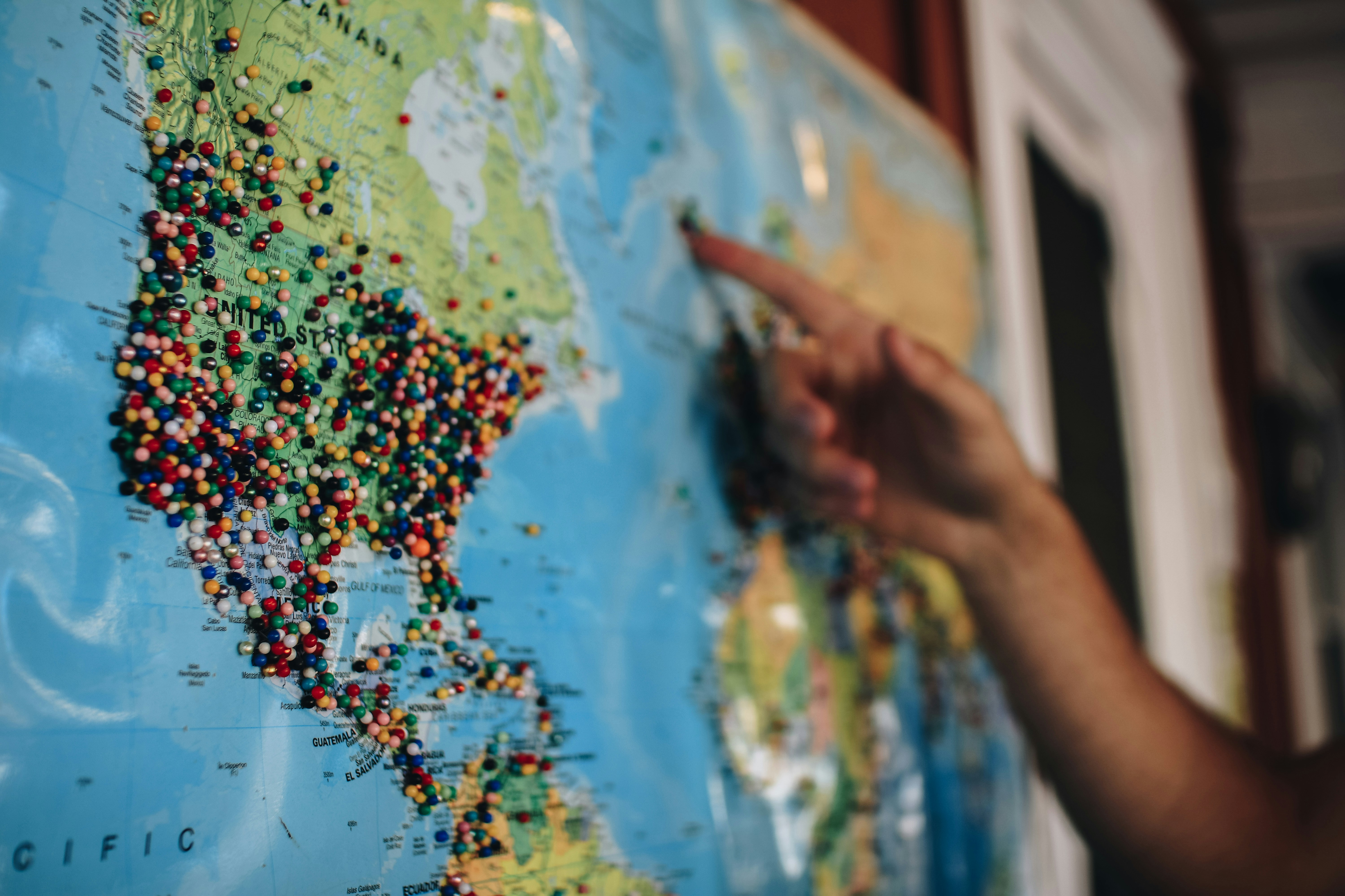 Hand pointing to a map with pins inside.