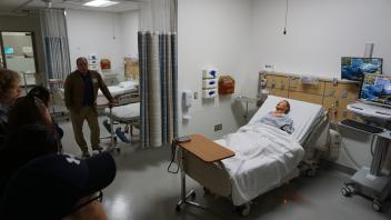 Attendees touring the Simulation Center at UC Davis Health, looking at a mannequin on a bed.