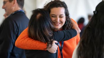Two attendees hugging and smiling