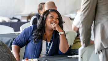 An attendee sitting down looks up at another attendee standing up.