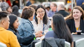 Attendees sitting at a table, conversing and smiling.