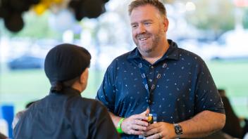 Two attendees smiling at each other. One attendee's back is turned away from the camera.