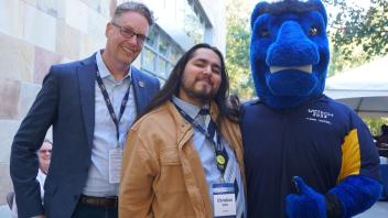 Attendees smiling with the UC Davis blue horse mascot, Gunrock