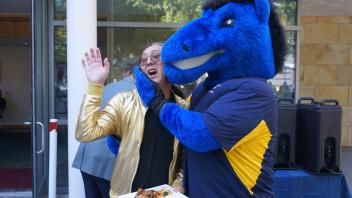 Attendees smiling with the UC Davis blue horse mascot, Gunrock