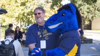 Attendee interlocking hands with the UC Davis blue horse mascot, Gunrock