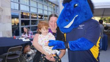 Attendees smiling with the UC Davis blue horse mascot, Gunrock