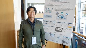 UC Tech poster presenter smiling with their poster presentation