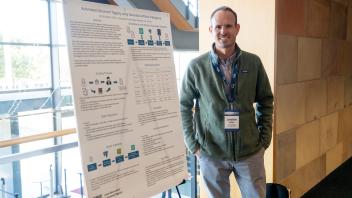 UC Tech poster presenter smiling with their poster presentation