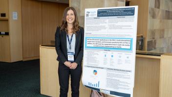 UC Tech poster presenter smiling with their poster presentation
