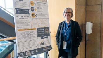 UC Tech poster presenter smiling with their poster presentation
