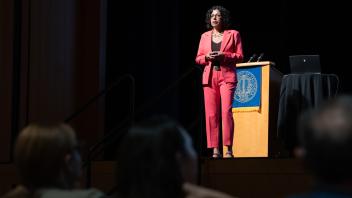Keynote speaker, Raissa D'Souza, giving her keynote address at UC Tech. She is wearing a red suit.