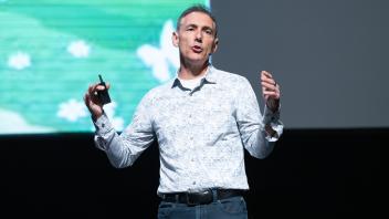 Tom Andriola giving his spotlight talk. His arms are at his sides.
