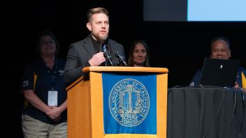UC Riverside representative, Matthew Gunkel, speaking on the podium during the Pass the Buck ceremony.