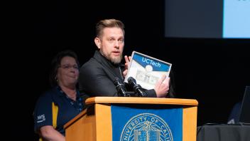 UC Riverside representative, Matthew Gunkel, speaking on the podium and holding the buck during the Pass the Buck ceremony.