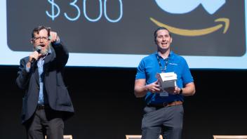 UC Tech MC, Andy Jones, and vendor raffle staff pointing and smiling to the crowd.