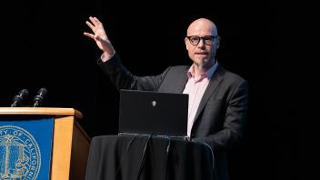 Keynote speaker, Martin Hilbert, giving his keynote address at UC Tech. Hilbert holds up one arm.