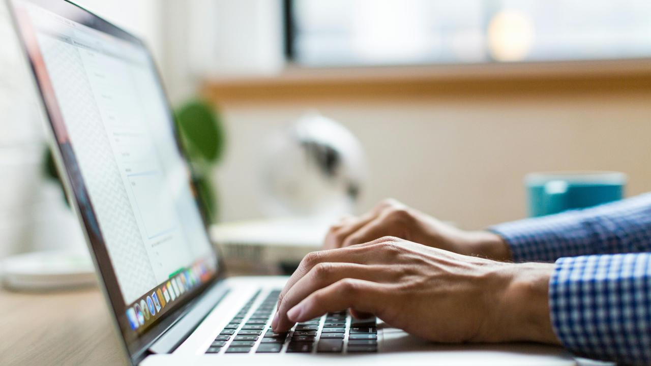 Hands typing on a Macbook