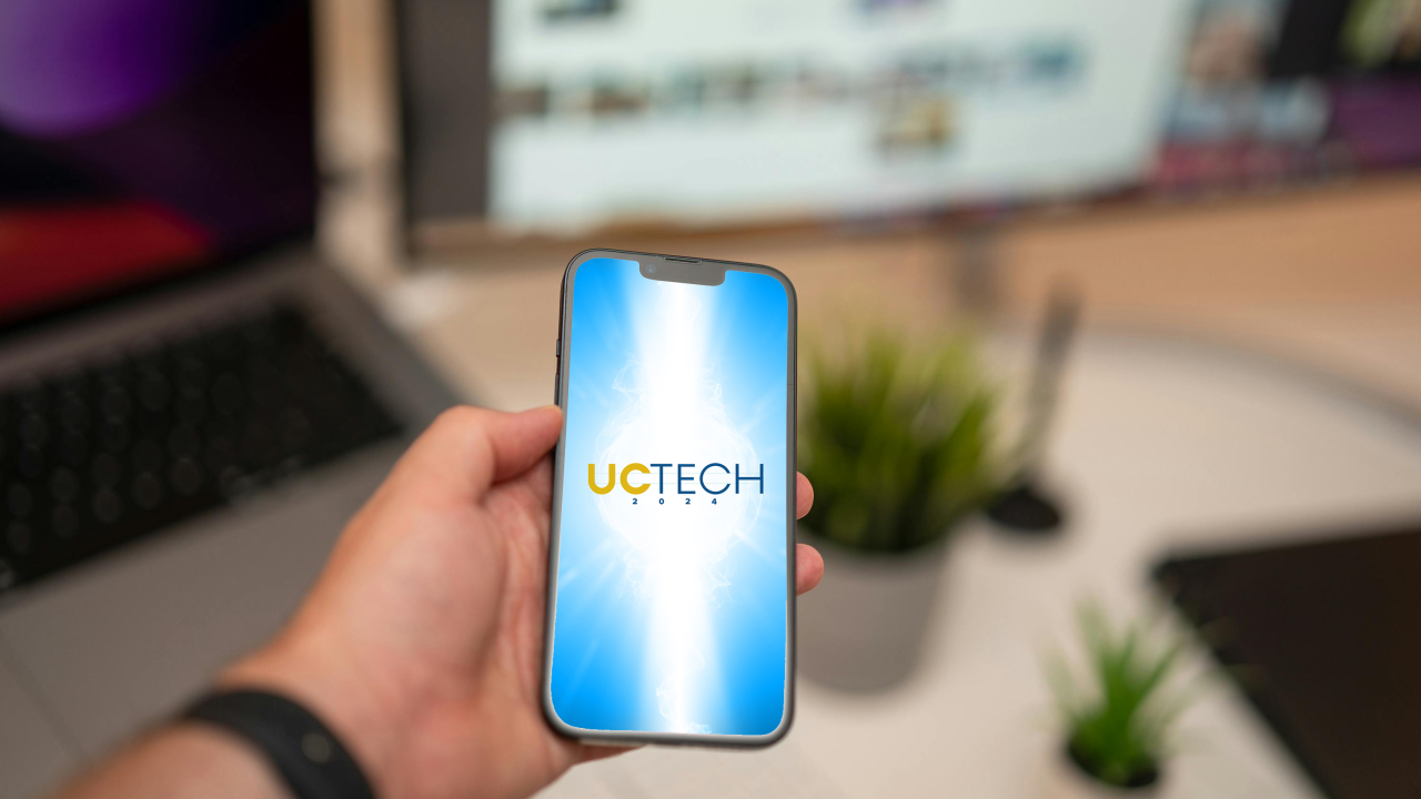 Hand holding a phone with the UC Tech app
